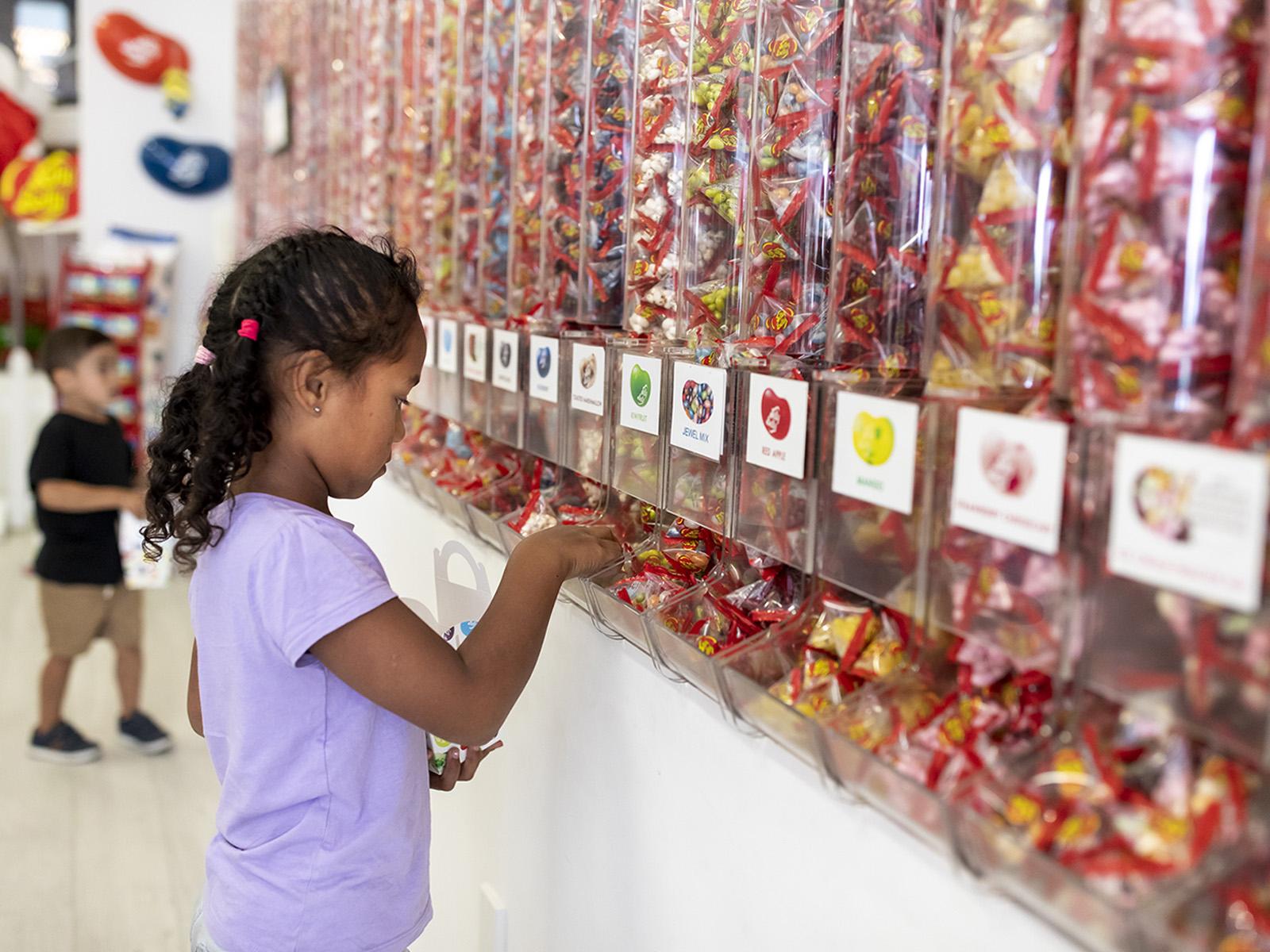 Image of a girl in a sweet store choosing jelly beans