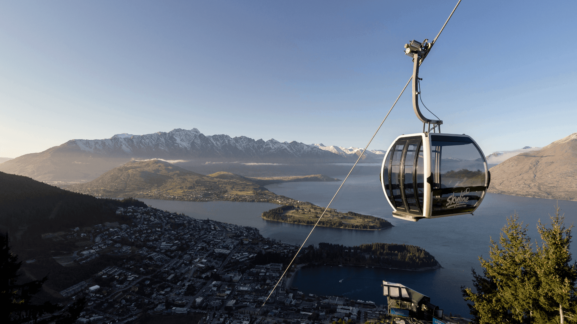 Gondola going up the mountain in Queenstown showing view of lake