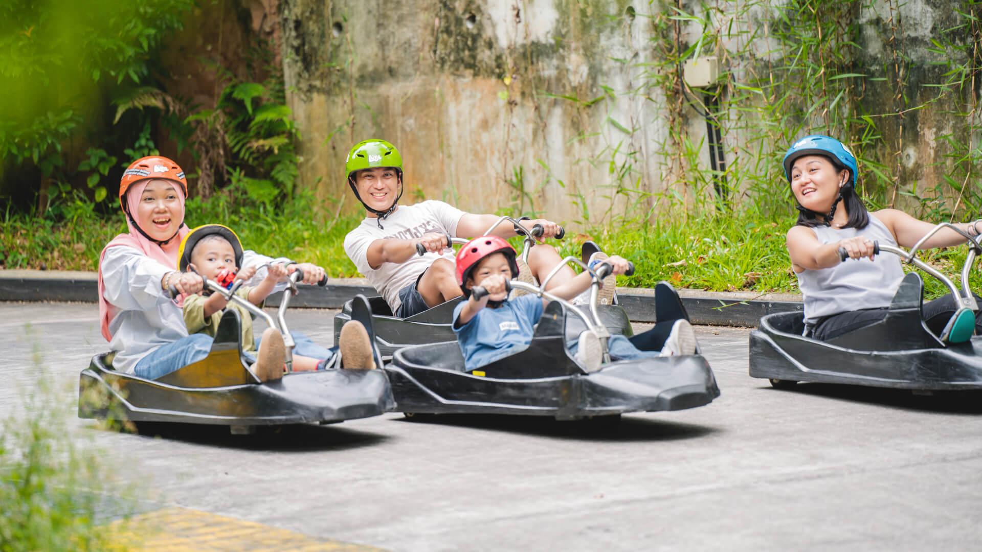 A family group rides down the tracks together with children riding in the same cart as an adult and one riding by himself.