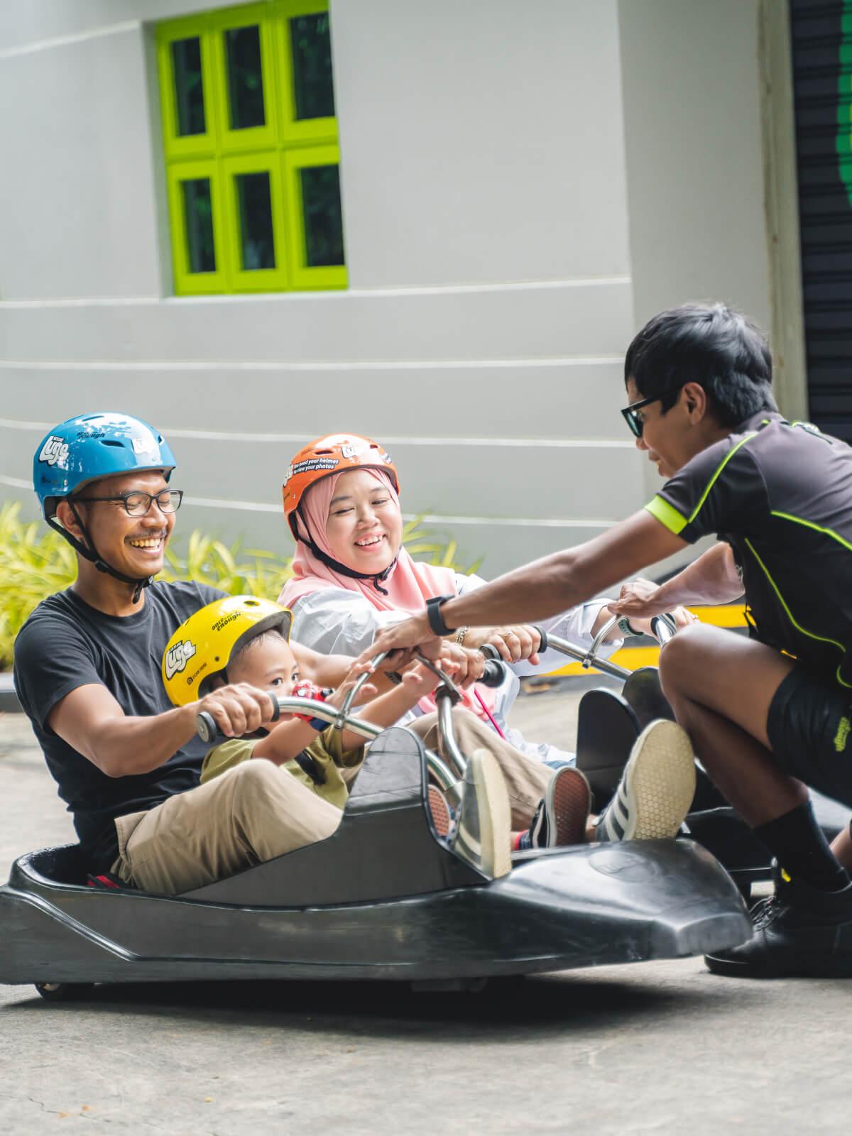 A Skyline Luge Singapore employee teaches a family how to use the Luge carts safely.