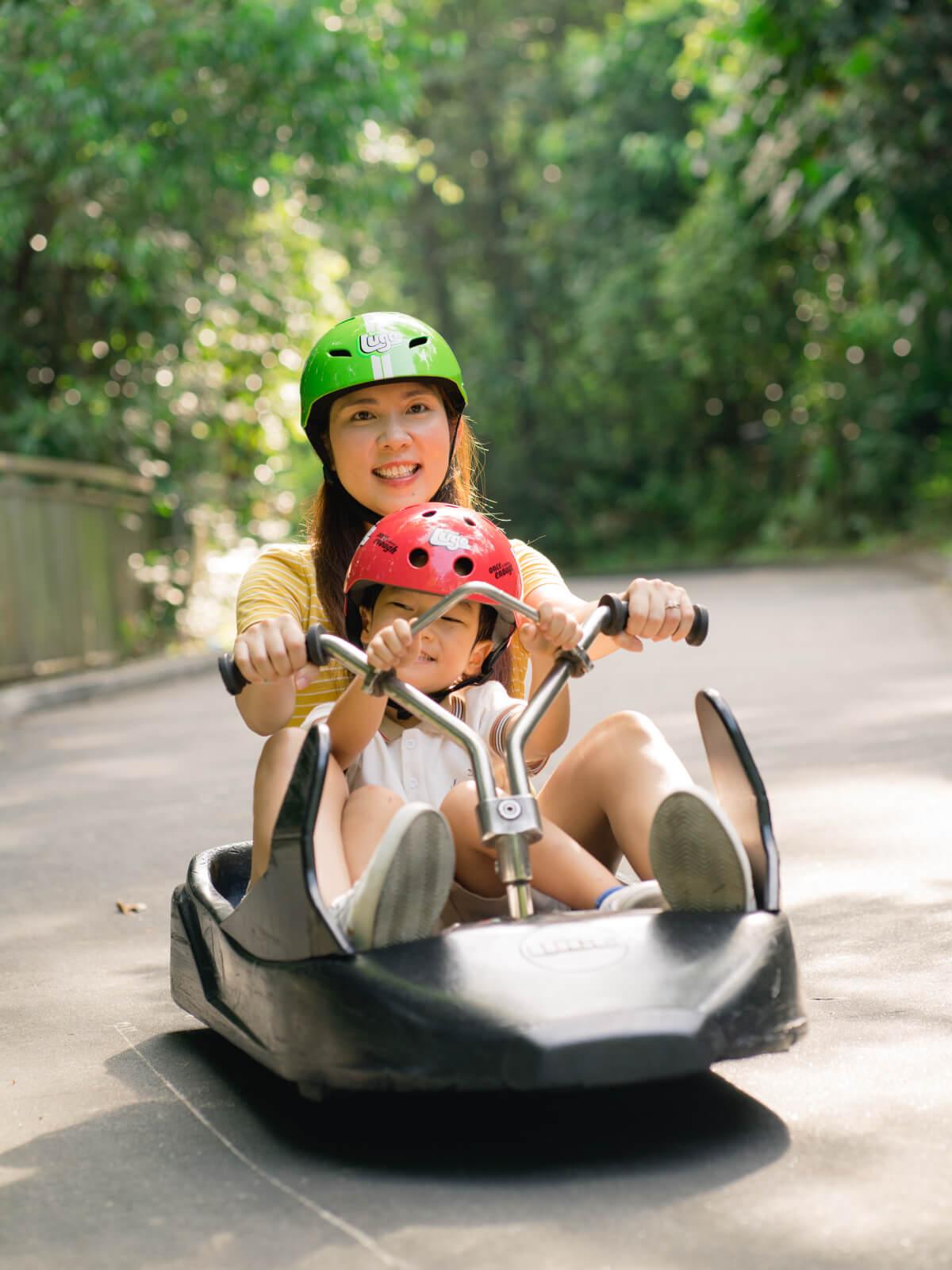 A mother and son ride the tracks in the same Luge cart.