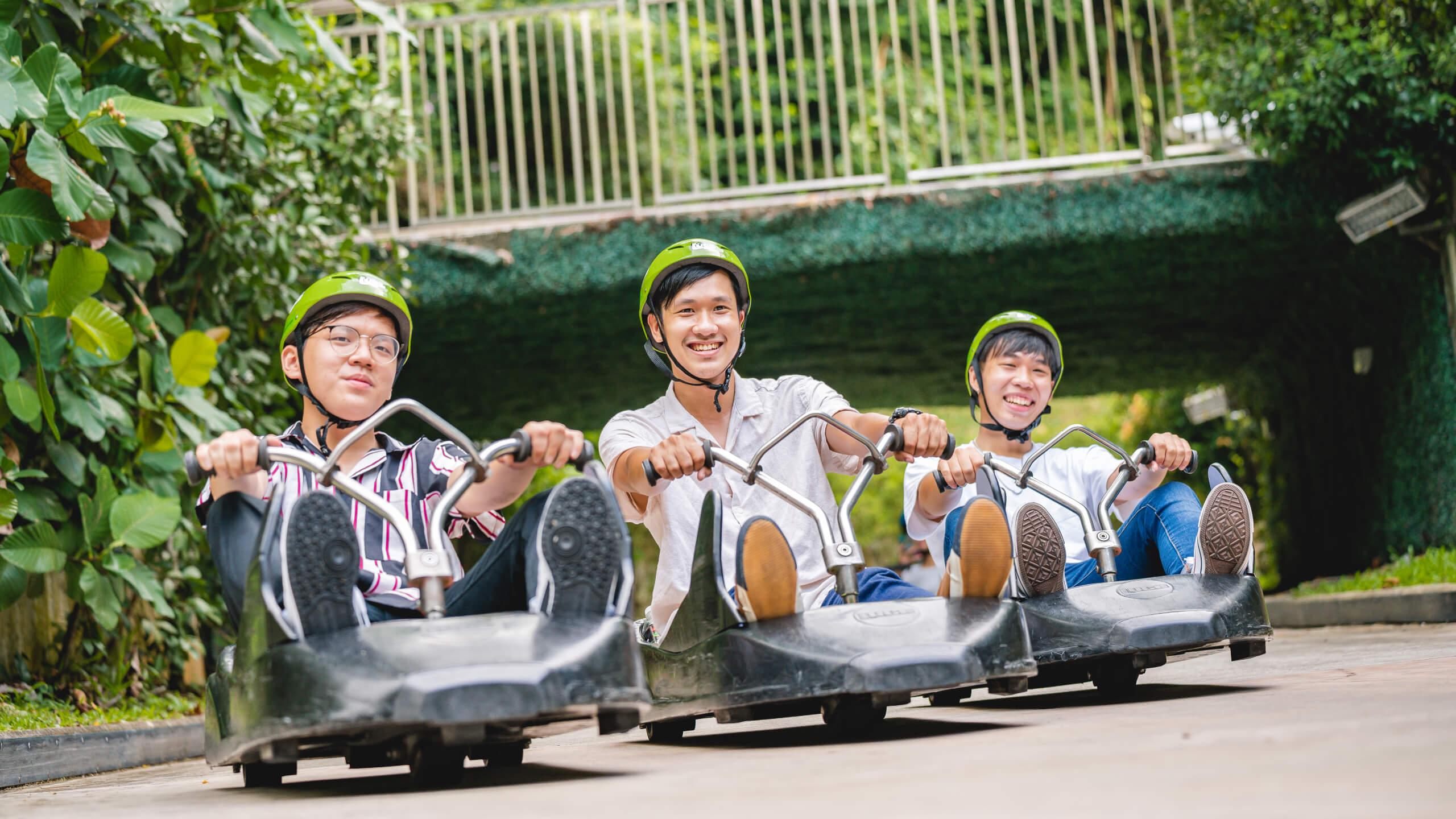 Three friends ride down the Luge tracks next to each other.