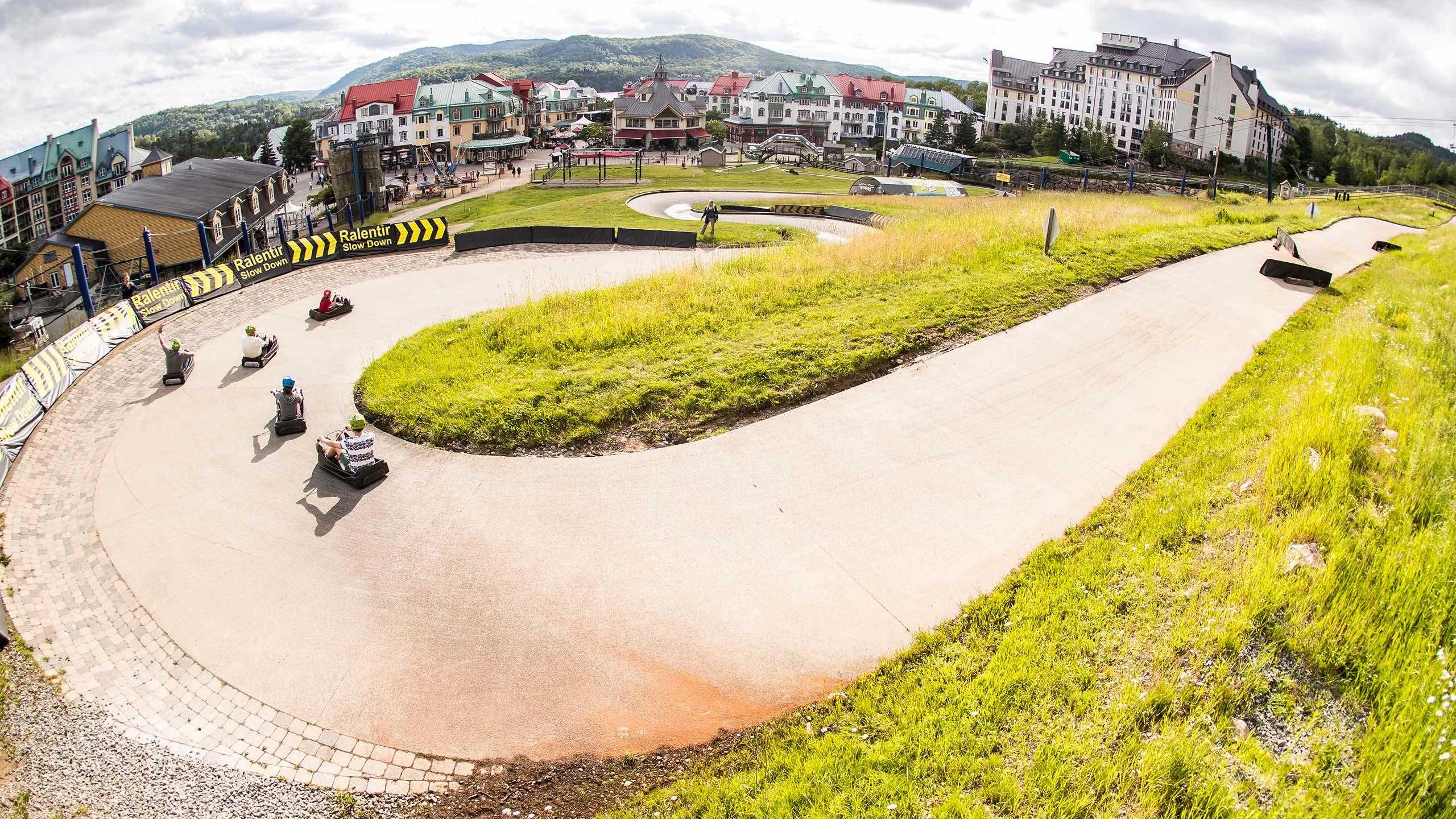 A group of customers ride around a large horseshoe corner at Skyline Luge Mont Tremblant.