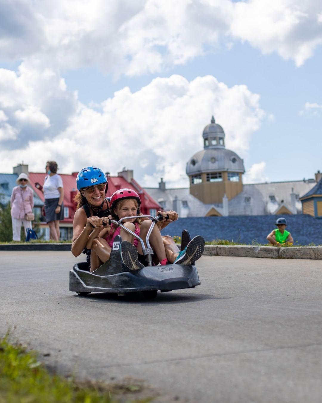 A mother rides down the Luge with her daughter in the same cart.