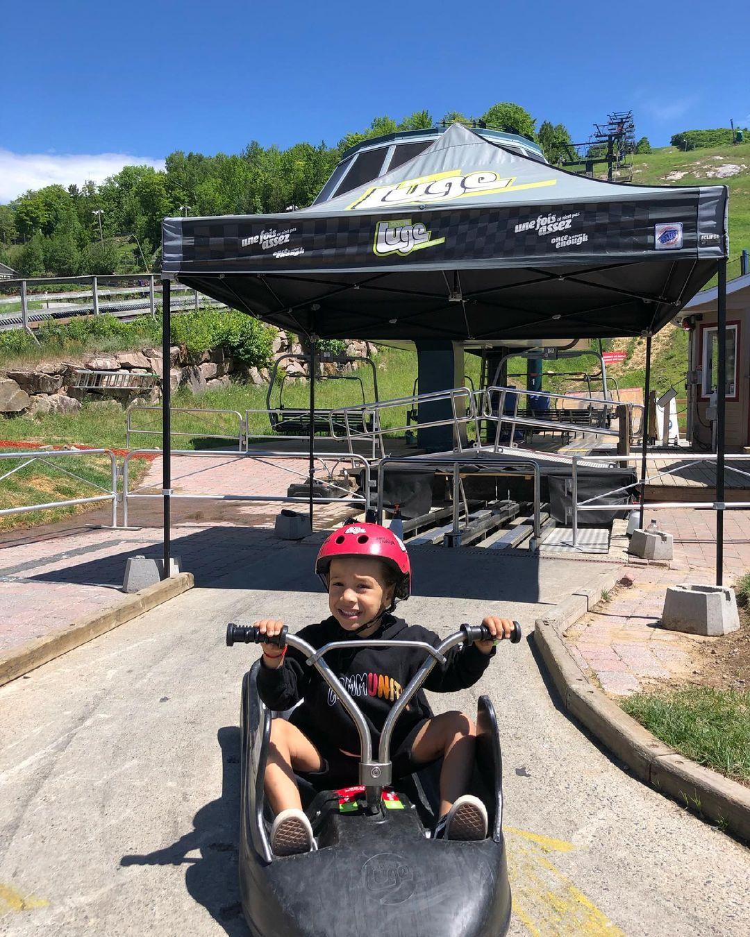 A small kid poses for a photo in his Luge cart at Skyline Luge Mont Tremblant.